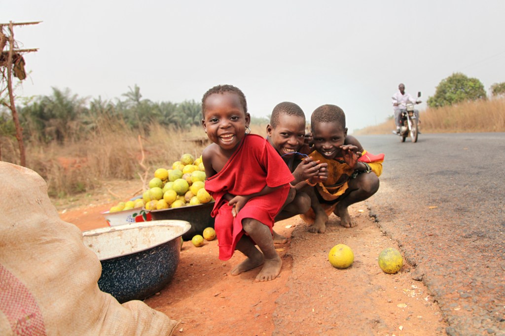 Nogle børn foran en butik med appelsiner på landevejen mellem Bohicon og Cové. Den lille pige har "skæremærker" på kinderne - ar som viser hvilken stamme hun hører til. Vejen er finansieret af Danida og blev bygget færdig i 2006. Den har betydet m