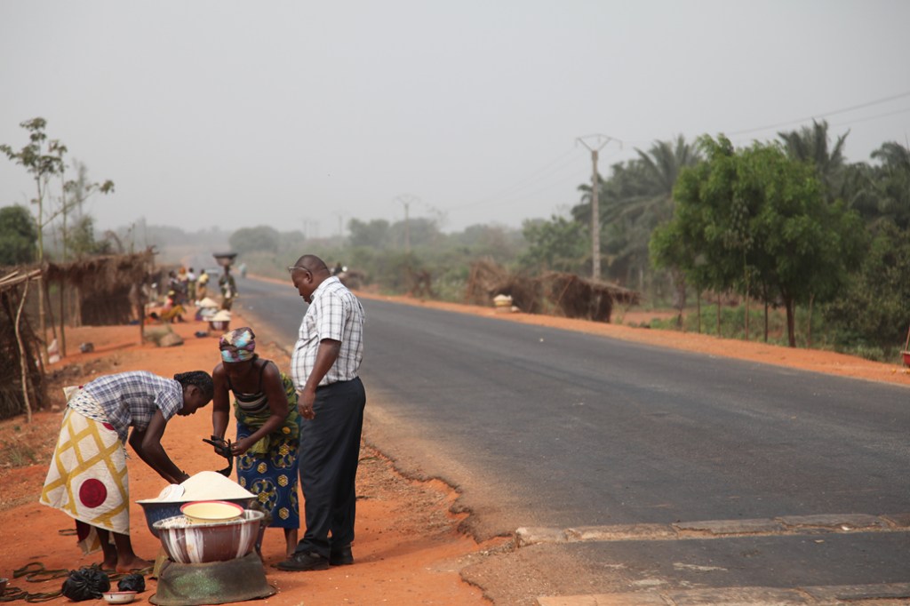 To kvinder er i gang med at sælge varer til en mand. Deres butik ligger ved landevejen mellem Bohicon og Cové som er finansieret af Danida og blev bygget færdig i 2006. Vejen har betydet meget mere trafik og dermed meget mere handel. Det er nemmere at